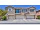 Exterior view of a three-story townhouse featuring a small balcony and a trio of garages in a contemporary style at 23 Hudson Canyon St # 3, Henderson, NV 89012