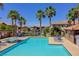 Community pool surrounded by palm trees and lounge chairs under a clear blue sky at 23 Hudson Canyon St # 3, Henderson, NV 89012