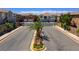 Community street view with palm trees, landscaped median, and gated entry to a neighborhood of modern homes at 23 Hudson Canyon St # 3, Henderson, NV 89012