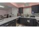 A Kitchen with stainless steel appliances, black cabinets, and contrasting countertops and backsplash, next to Living Room at 2725 S Nellis Blvd # 2168, Las Vegas, NV 89121