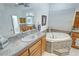 Bathroom featuring an oval soaking tub with tiled surround, single vanity and tile flooring at 3451 Sagebrush Ave, Pahrump, NV 89048
