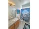 Bathroom with single sink with wood cabinets, tile countertop, and blue wolf themed shower curtain at 3451 Sagebrush Ave, Pahrump, NV 89048