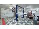Spacious garage featuring a car lift, multiple doors, storage racks, and checkered flooring at 3451 Sagebrush Ave, Pahrump, NV 89048