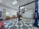 Garage interior featuring a car lift, storage, checkered floors, and three garage doors at 3451 Sagebrush Ave, Pahrump, NV 89048