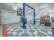 Spacious garage featuring a car lift, multiple doors, storage racks, and checkered flooring at 3451 Sagebrush Ave, Pahrump, NV 89048