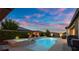 Backyard with a sparkling pool, integrated spa, and lush landscaping at dusk, perfect for relaxation at 6192 Lautman Ridge Ct, Las Vegas, NV 89141