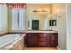 Bright bathroom featuring a double vanity, soaking tub, and plantation shutters at 62 Myrtle Springs Ct, Las Vegas, NV 89148