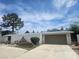 Neutral home featuring two-car garage, decorative yard art and desert landscaping in a sunny setting at 6215 Darby Ave, Las Vegas, NV 89146
