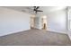 Large, carpeted bedroom with a ceiling fan and view of a kitchenette with white cabinets at 6420 Rosemount Ave, Las Vegas, NV 89156