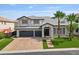 Stunning two-story home featuring a brick driveway, well-manicured lawn, and beautiful palm trees at 6639 Tranquil Seas Ct, Las Vegas, NV 89139