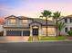 Two-story home with three-car garage, green lawn, and mature palm trees at dusk at 6639 Tranquil Seas Ct, Las Vegas, NV 89139