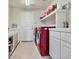 Efficient laundry room with red washer/dryer, white cabinets and shelving, and door to exterior at 6639 Tranquil Seas Ct, Las Vegas, NV 89139