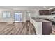 Open-concept living area with wood-look floors, sliding glass doors to balcony, and kitchen area at 6952 Crescent Gold St, North Las Vegas, NV 89086