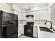 Updated kitchen with white cabinets, quartz countertops, and black appliances at 7566 Glowing Ember Ct # 101, Las Vegas, NV 89130