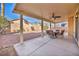 Covered patio featuring an outdoor dining set, ceiling fan, and decorative rock landscaping at 7886 Palace Monaco Ave, Las Vegas, NV 89117