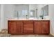 Bright bathroom featuring a double sink vanity with wood cabinets, a large mirror and modern fixtures at 7908 Morning Gallop Ct, Las Vegas, NV 89131