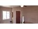Bedroom with textured cinder block walls, a window and wooden door with a full-length mirror at 829 Dover Pl, Las Vegas, NV 89107