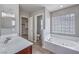 Bright bathroom featuring a soaking tub with glass block window, vanity, and a walk-in closet at 9005 Semillon St, Las Vegas, NV 89148