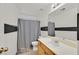 Well-lit bathroom features a shower with grey curtain, toilet, and vanity with mirror at 9105 White Eyes Ave, Las Vegas, NV 89143