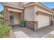 Inviting front entrance with stone accents, a two-car garage, and brick driveway at 9853 Bangalore Ct, Las Vegas, NV 89148