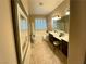 Bright bathroom featuring a tub, double sink vanity, plantation shutters, and tile flooring at 10248 Maggira Pl, Las Vegas, NV 89135