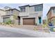 Modern two-story home featuring a stone facade, brick driveway, and a teal front door at 11840 Pelican Butte Ave, Las Vegas, NV 89138