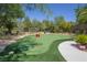 A backyard putting green featuring artificial turf and mature landscaping on a sunny day at 11926 Port Labelle Dr, Las Vegas, NV 89141