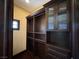 Custom closet with dark wood cabinets, drawers, shelving, glass-fronted cabinets, and a small window at 1800 Amarone Way, Henderson, NV 89012