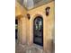 Arched doorway with custom stonework, decorative lighting, and travertine tile flooring at 1800 Amarone Way, Henderson, NV 89012