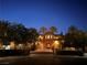 Striking home at dusk, featuring an ornate gate, lush landscaping, and warm exterior lighting at 1800 Amarone Way, Henderson, NV 89012