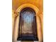 Elegant front door with security system, ornate ironwork, and stone arched entryway at 1800 Amarone Way, Henderson, NV 89012