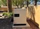 View of the generator in the backyard with brickwork and greenery at 1800 Amarone Way, Henderson, NV 89012