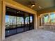 This covered patio showcases decorative columns, travertine tile flooring, and large sliding glass doors at 1800 Amarone Way, Henderson, NV 89012