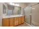 Bathroom with double sink vanity, large mirror, oak cabinets, and a walk-in shower with glass doors at 2221 River Grove Dr, Henderson, NV 89044