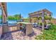 Backyard featuring a built-in outdoor kitchen, bar seating, and a cozy pergola-covered seating area at 280 Via Del Duomo, Henderson, NV 89011