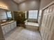 Bright bathroom with dual sinks, granite counters, a soaking tub, and glass-enclosed shower at 316 Lingering Ln, Henderson, NV 89012