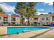 Community swimming pool surrounded by buildings and lush trees under a bright blue sky at 4860 Nara Vista Way # 104, Las Vegas, NV 89103