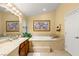 A bathroom area with a soaking tub, dual vanity sinks, and decorative fixtures, perfect for relaxation at 5940 Vizzi Ct, Las Vegas, NV 89131