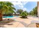 A spacious backyard with patterned concrete, palm trees, and a relaxing pool area in the distance at 6779 Rainstorm Ridge Ave, Las Vegas, NV 89131