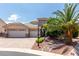 Inviting single-story home featuring a three-car garage, stone accents, and mature palm tree landscaping at 6779 Rainstorm Ridge Ave, Las Vegas, NV 89131