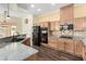 Modern kitchen with granite counters, wooden cabinets, and black appliances at 6779 Rainstorm Ridge Ave, Las Vegas, NV 89131