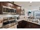 Cozy kitchen featuring granite countertops, stainless steel appliances, and dark wood cabinets at 6807 Satin Silver Ct, North Las Vegas, NV 89086