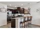 Bright kitchen with stainless steel refrigerator, granite counters and dark wood cabinets and bar seating at 6807 Satin Silver Ct, North Las Vegas, NV 89086