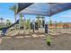 Colorful playground featuring a slide, climbing frames, and swings, sheltered by a large sunshade in a community at 6807 Satin Silver Ct, North Las Vegas, NV 89086