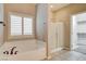 A bathroom features a soaking tub and glass shower and access to a walk-in closet at 741 Flowing Meadow Dr, Henderson, NV 89014