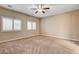 A neutral bedroom features two windows, a ceiling fan, and neutral carpet at 741 Flowing Meadow Dr, Henderson, NV 89014