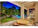 Beautifully lit backyard featuring a sparkling pool, lush landscaping, and outdoor dining area, perfect for evening relaxation at 7988 Pinnacle Peak Ave, Las Vegas, NV 89113