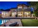 Elegant backyard with a sparkling pool, stone patio, and outdoor seating area at dusk at 7988 Pinnacle Peak Ave, Las Vegas, NV 89113