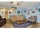 Welcoming living room with a comfortable couch, wood-look flooring, and beach-themed decor at 9236 Keystone Ridge Ave, Las Vegas, NV 89148