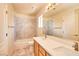 Well-lit bathroom featuring double sinks, marble wall tiles, and a shower-tub combo at 9413 Cedar Heights Ave, Las Vegas, NV 89134